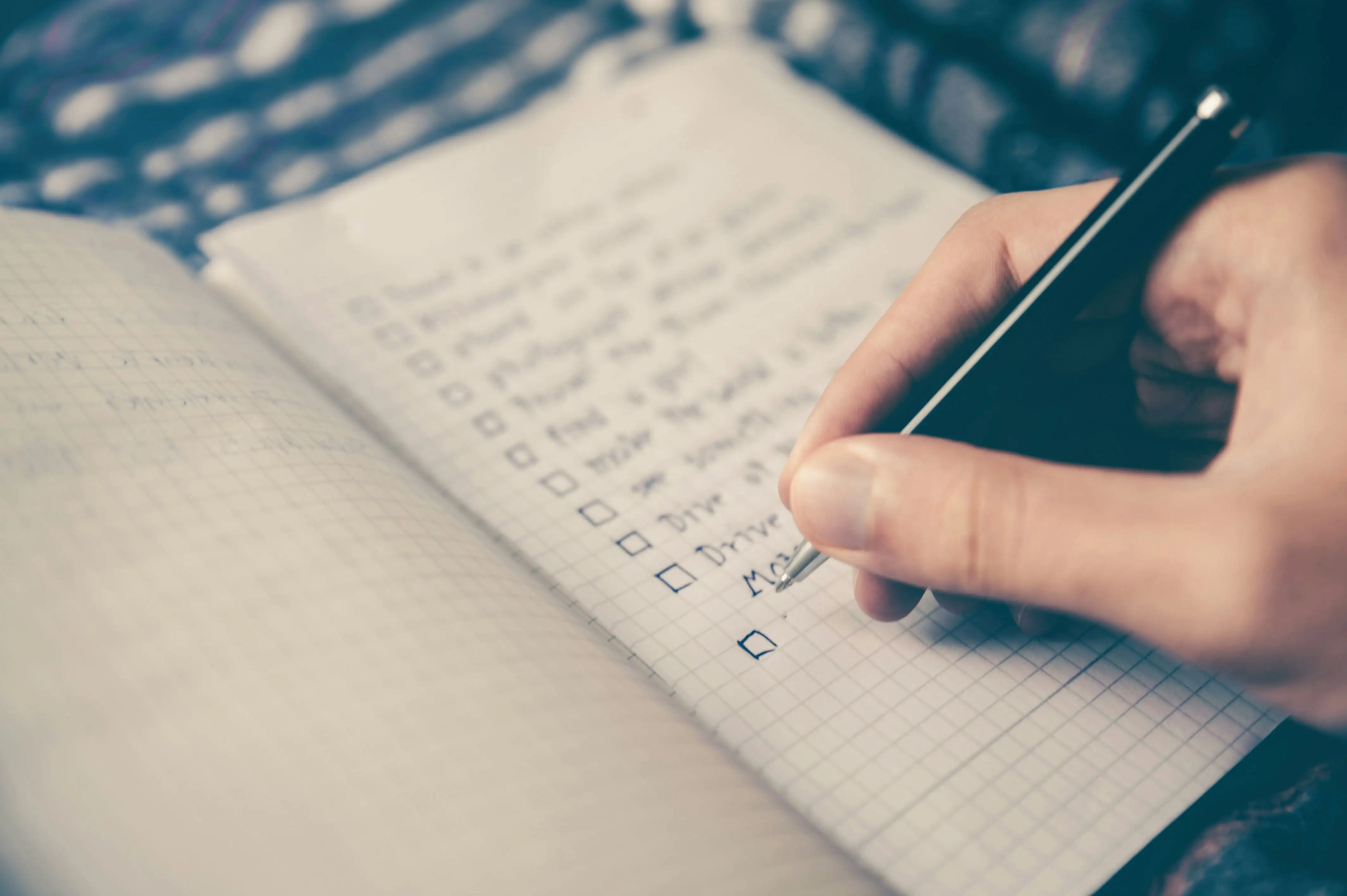 Person writing a moving checklist in a notebook