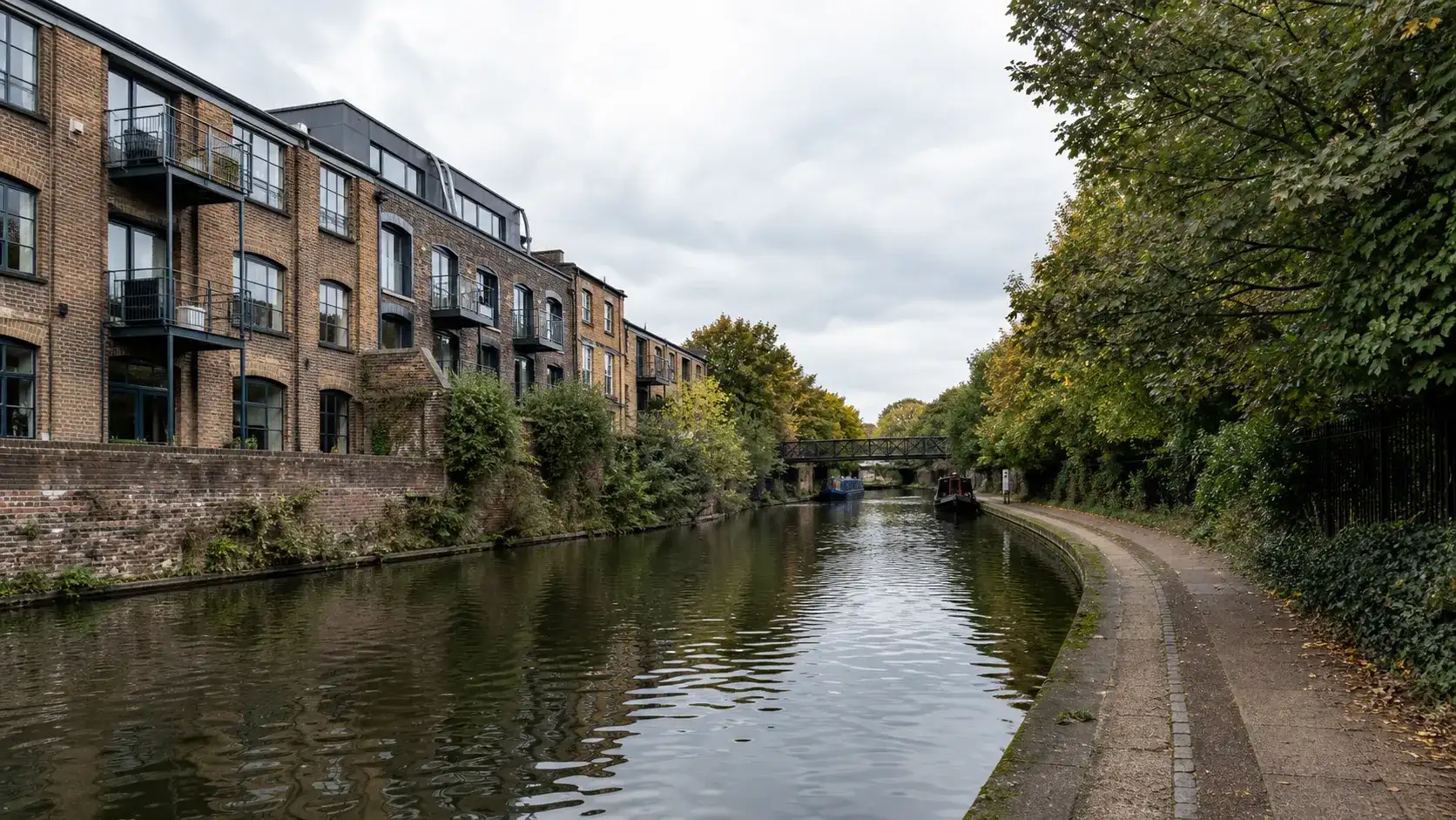 A canal-side residential scene with brick buildings and mature trees in Camden Town, London