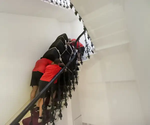 Redpath piano moving specialists using protective equipment to lift and secure a grand piano